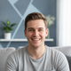 Headshot of a smiling young German man looking at the camera, conveying trust and happiness.