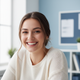 Close-up portrait of a smiling female college student, in her mid-20s, with natural lighting and a soft blue and white backgr